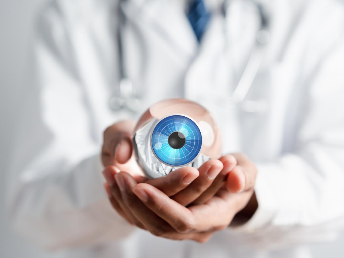 Doctor in a white coat holding a glass eye. 